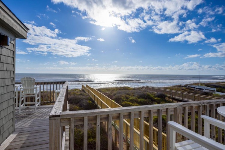 Oceanfront location with boardwalk access to the shore, framed by coastal dunes and open skies.