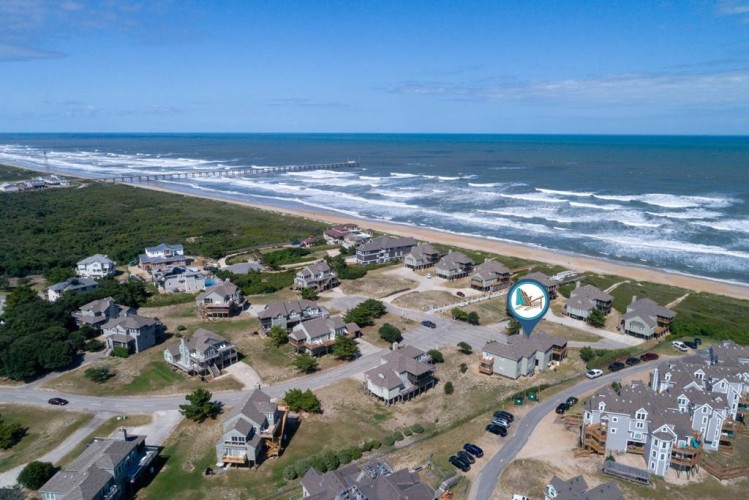 This oceanfront community offers direct beach access and stunning coastal views, situated along a pristine stretch of shoreline with neighboring vacation homes nearby.