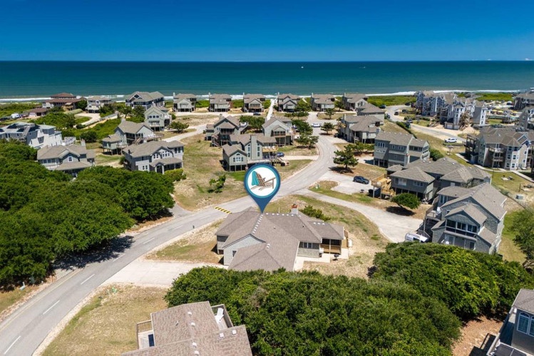 Aerial view of a beachfront neighborhood with coastal homes, tree-lined streets, and direct ocean access just moments away.
