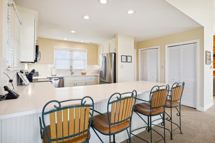Settle into your breakfast bar seats and savor morning coffee while sunlight pours through the windows. The open kitchen invites you to cook with ease, surrounded by gleaming counters and modern appliances ready for your culinary adventures.