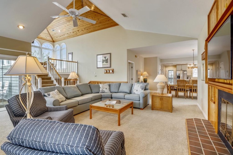 Relax in your spacious living room with cathedral ceilings and warm wood accents. Sink into the plush sectional sofa, gather around the fireplace, and enjoy the open flow to your dining area.