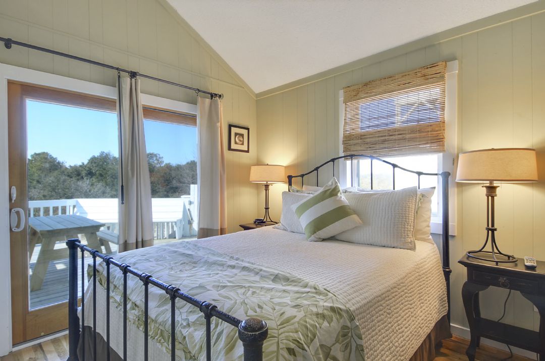Wake up to treetop views and soft natural light filtering through your private balcony doors. This serene bedroom offers a peaceful retreat with coastal-inspired decor and a plush bed waiting to cradle you after your adventures.