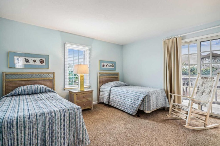 Settle into your peaceful retreat with twin beds dressed in coastal linens, soothing blue tones, and a private balcony where relaxation awaits.