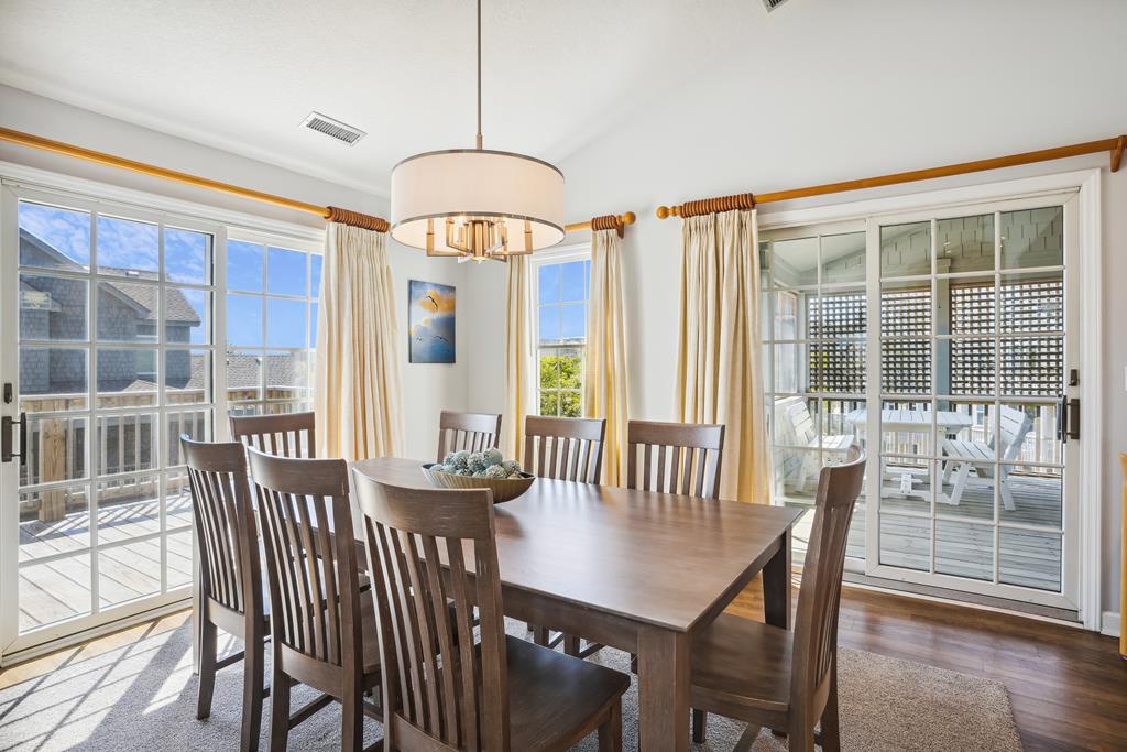 Gather around this inviting dining table where sunlight streams through floor-to-ceiling windows, framing your meals with views of the coastal retreat beyond. Perfect for sharing stories over fresh-caught seafood or morning coffee.