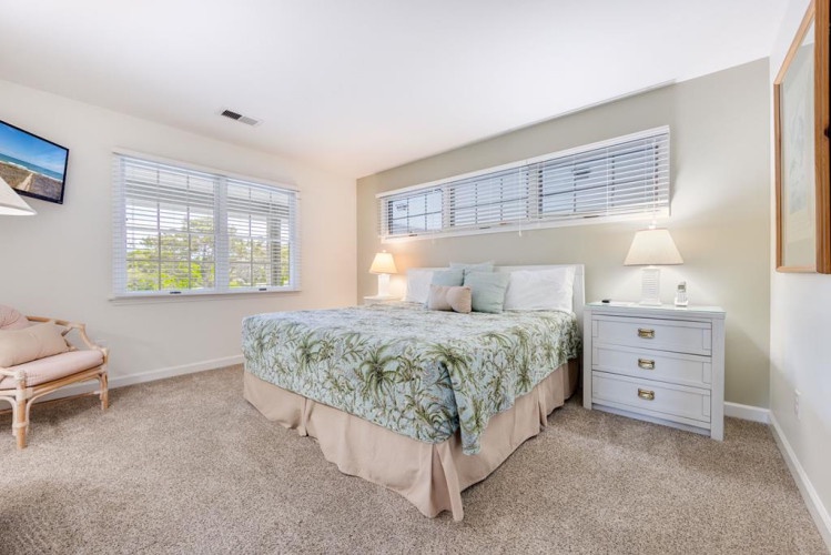 Your bright, peaceful bedroom awaits with soft natural light, plush bedding, and a cozy accent chair—perfect for unwinding after a day of exploring.