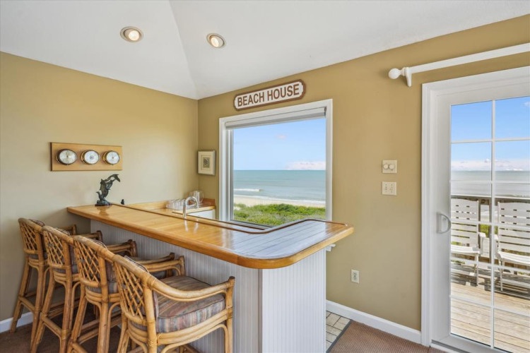Your breakfast bar overlooks endless ocean views through this beach house window, where mornings begin with sea breezes and the rhythmic sound of waves rolling ashore.