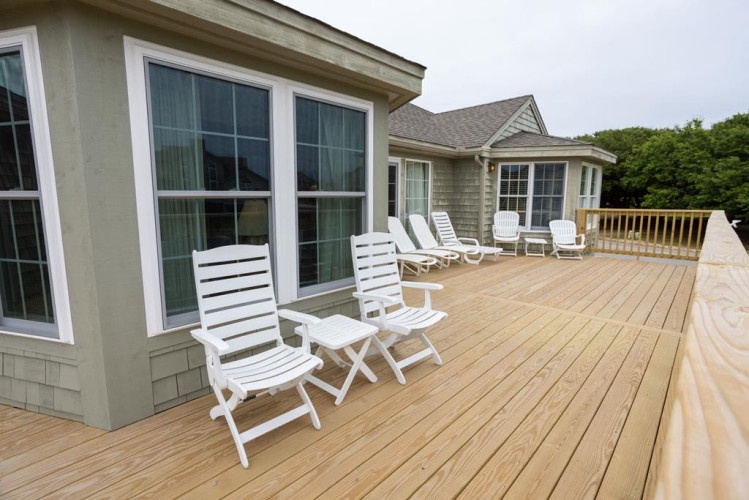 Spacious deck with white lounge chairs, framed by lush greenery—your perfect spot to relax, soak up the sun, and unwind outdoors.