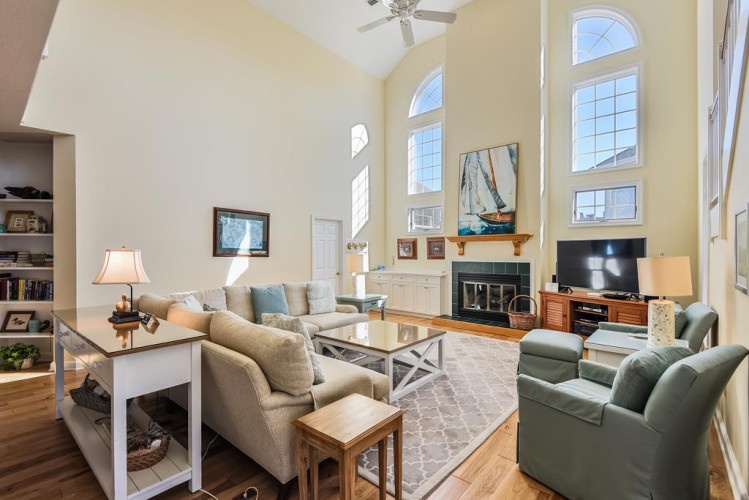 Settle into this bright, airy living room where soaring ceilings and sunlight invite you to unwind. Relax on plush seating or gather around the fireplace for a cozy evening in.