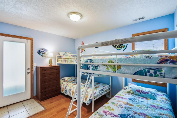 Two cozy bunk beds make this cheerful room perfect for kids to share. Bright ocean-themed bedding and playful fish decor add a fun, beachy vibe.