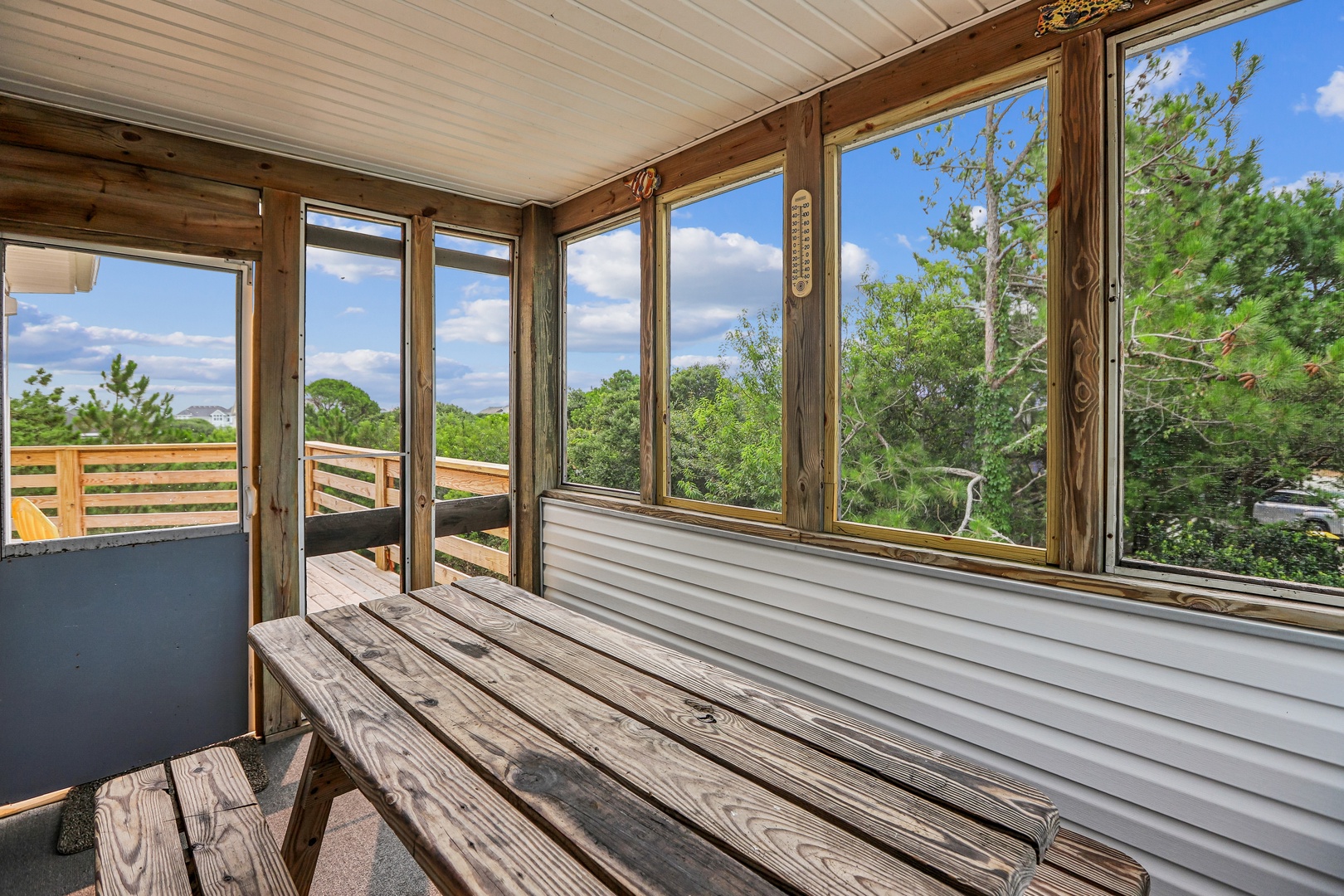 Step onto your private screened porch and breathe in the fresh air. Warm wooden beams frame sweeping views of lush treetops and open sky, creating a peaceful retreat where you can unwind.