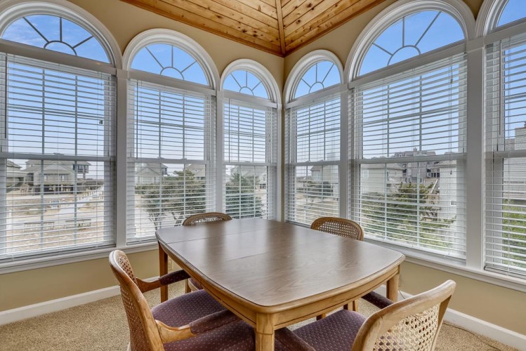 Picture yourself enjoying meals at this bright dining table, surrounded by elegant arched windows that frame peaceful neighborhood views and fill the space with natural light.