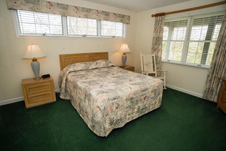 Slip into your peaceful retreat with a plush queen bed, warm bedside lighting, and soft natural light filtering through the windows—your restful escape awaits.