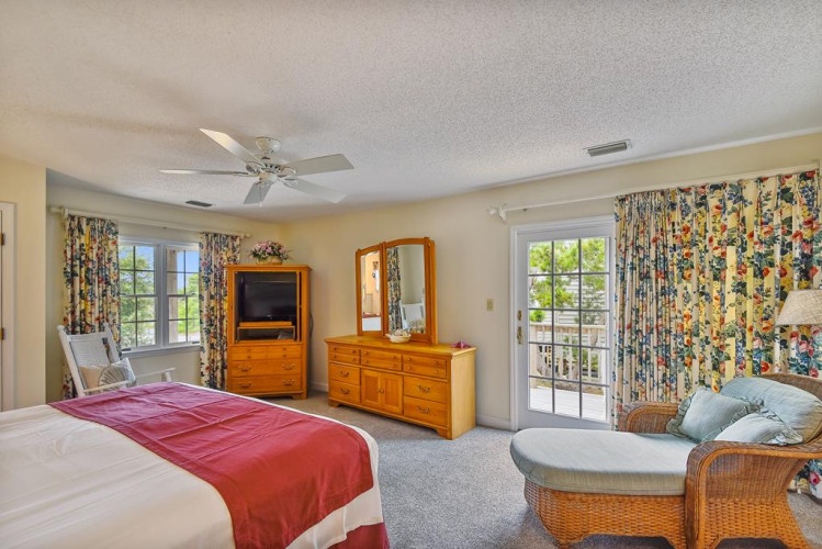 Wake up to bright windows and cozy comfort in your spacious bedroom with natural light streaming through floral drapes. Enjoy your private balcony access and ceiling fan overhead.