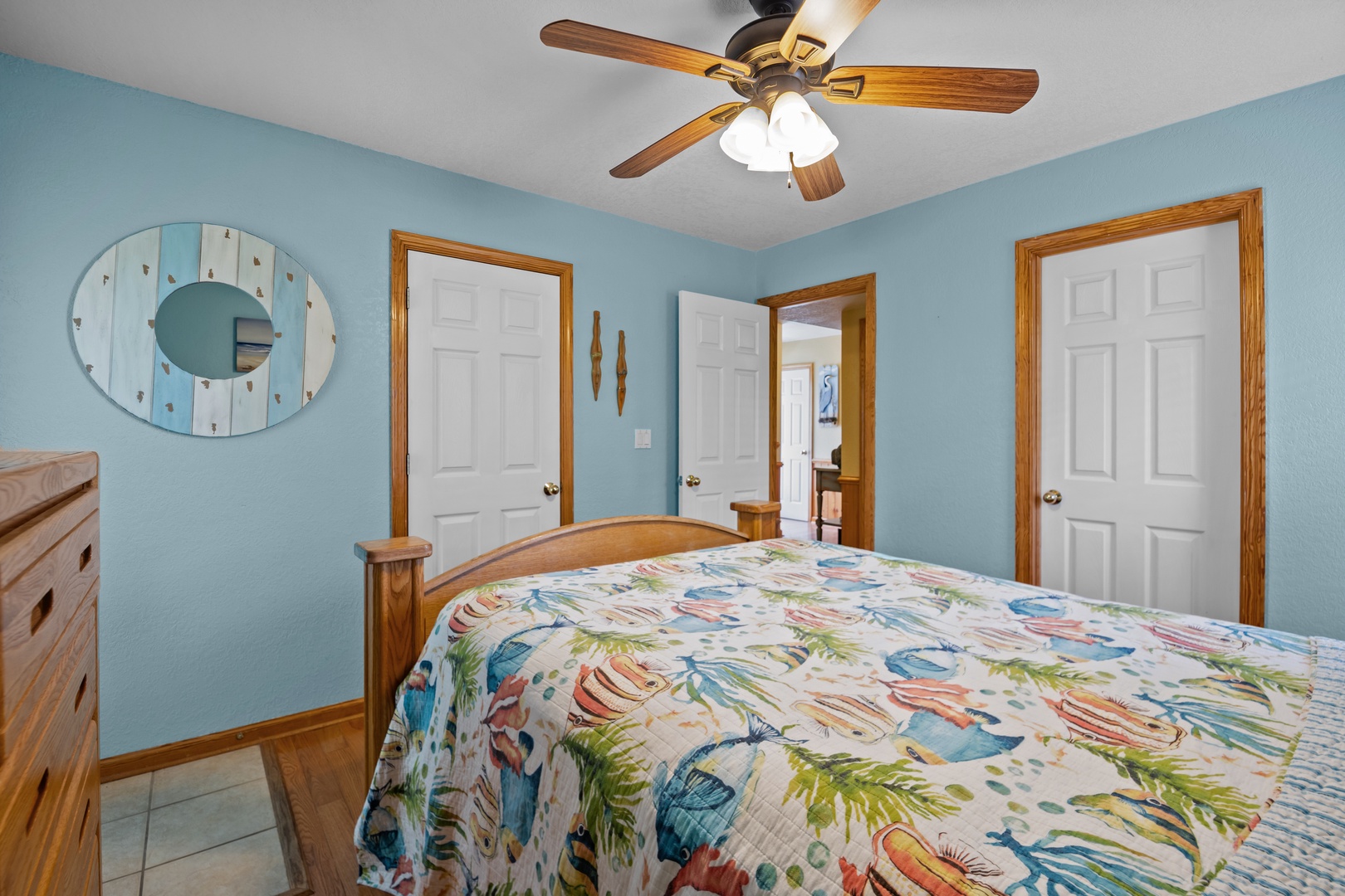 Drift off in this cheerful coastal bedroom where soft blue walls and tropical linens create a beachy, laid-back vibe perfect for your seaside escape.