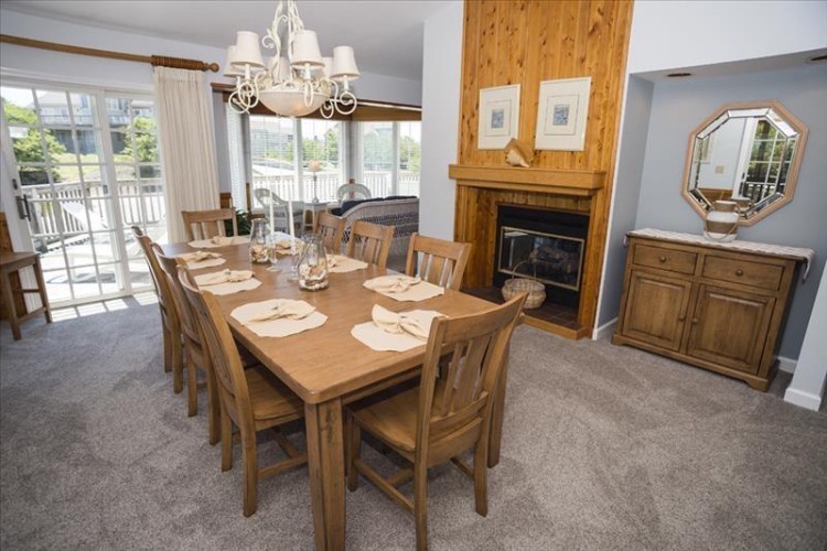 Gather around this inviting dining table where your group can share memorable meals together. Natural light streams through the patio doors, and a cozy fireplace adds warmth to your dining experience.