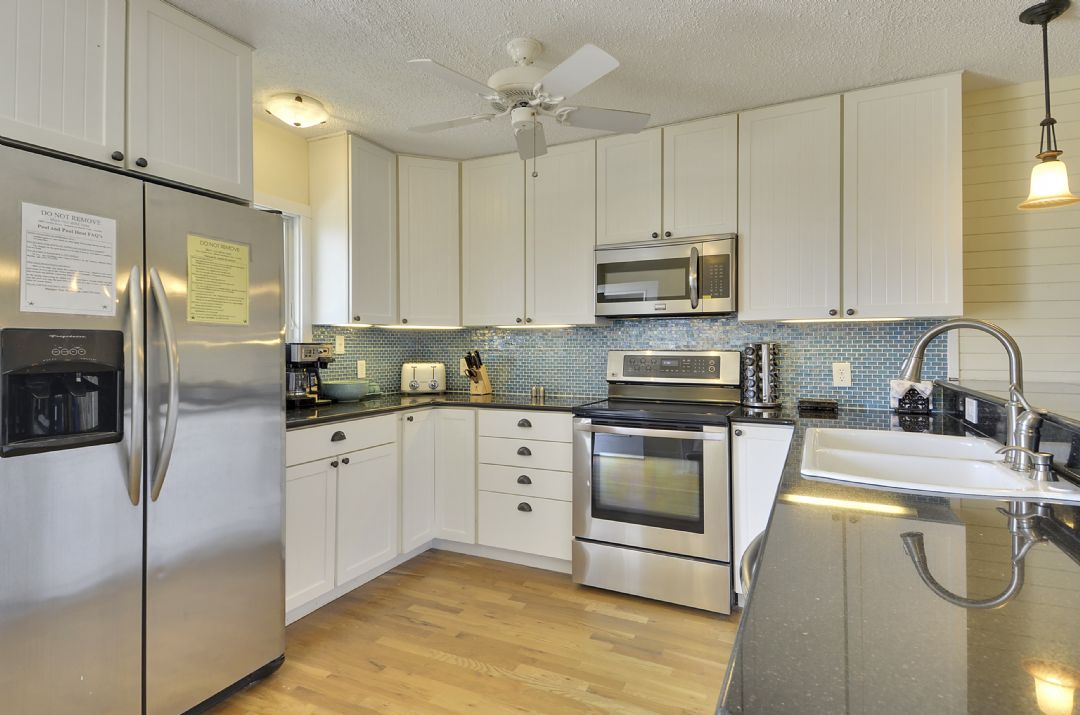 Whip up your favorite meals in this bright, fully equipped kitchen with stainless appliances, granite countertops, and a stylish blue mosaic backsplash that adds coastal charm.