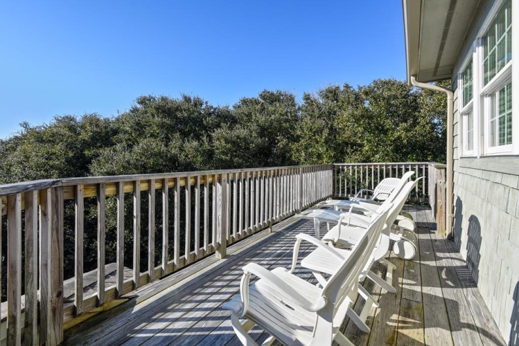 Your private balcony overlooks lush treetops, offering a peaceful spot to relax in the sun with comfortable lounge chairs and gentle coastal breezes.