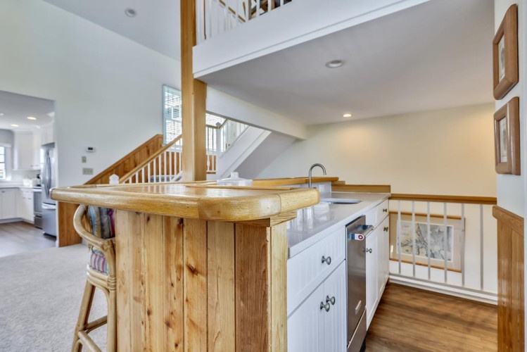 Your home away from home features an open-concept layout with warm wood accents, a convenient island bar, and a loft overlooking the bright, welcoming living spaces below.