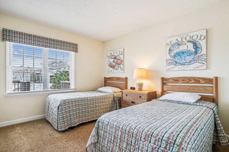 Your coastal-themed bedroom features two comfortable twin beds, warm natural light, and charming nautical artwork—perfect for relaxing after beach adventures or quality time with family.