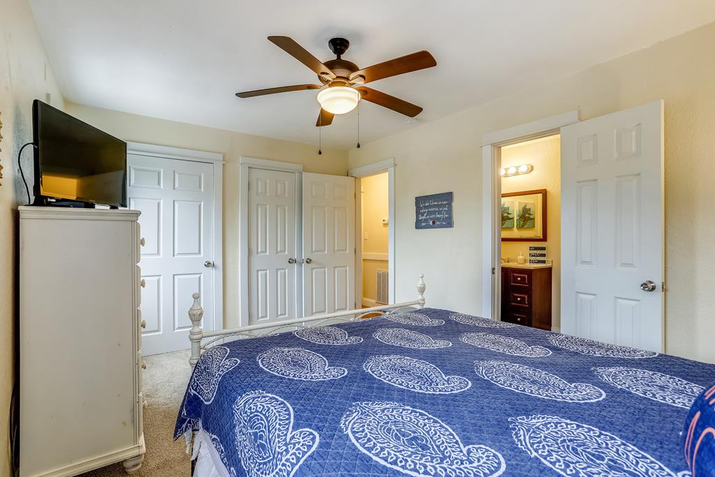 Your cozy bedroom features a comfortable bed, ceiling fan for gentle breezes, flat-screen TV, and closet space. Enjoy direct access to your private bathroom for added convenience during your stay.