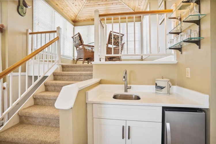 Your charming loft-style retreat features a convenient kitchenette with modern appliances, opening to a cozy upstairs seating nook perfect for unwinding with a book or morning coffee beneath soaring cathedral ceilings.