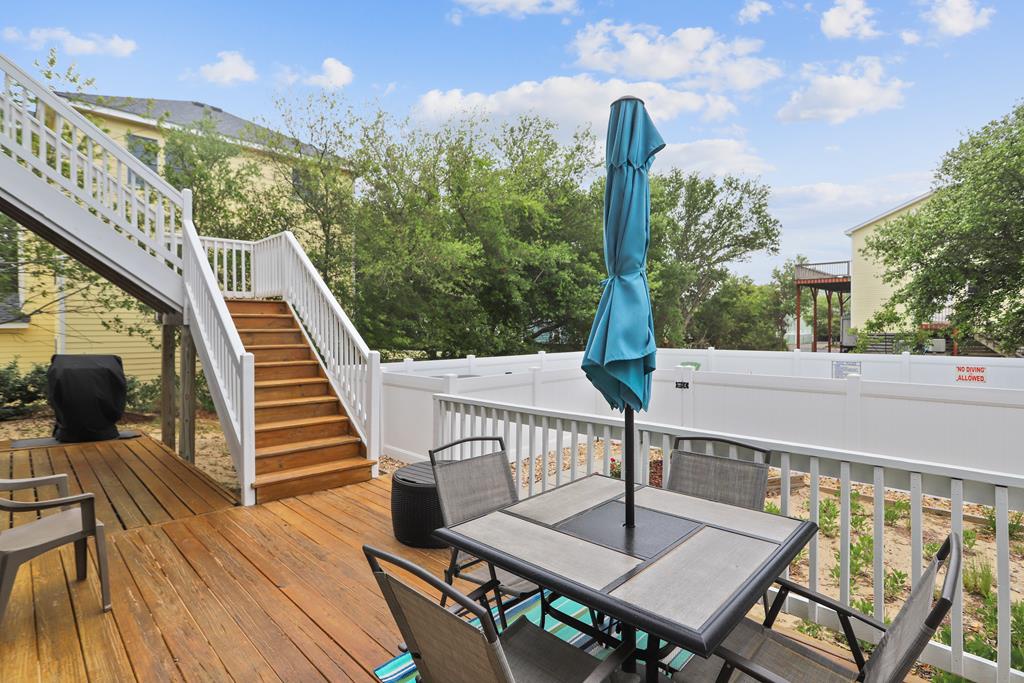 A spacious wooden deck with outdoor dining and stairs leading to upper levels—perfect for morning coffee, alfresco meals, and enjoying the fresh air surrounded by greenery.