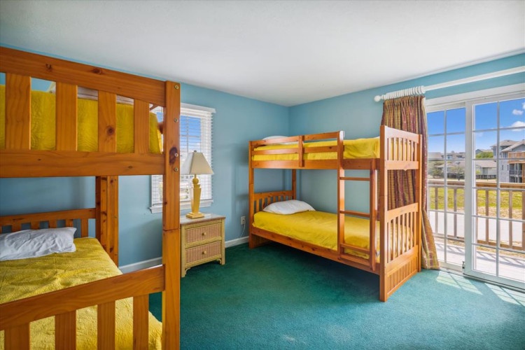 Your group will love this cheerful bunk room, where golden bedding and calming blue walls create a bright, welcoming retreat. Natural light pours through the glass door, offering a sunny balcony escape.
