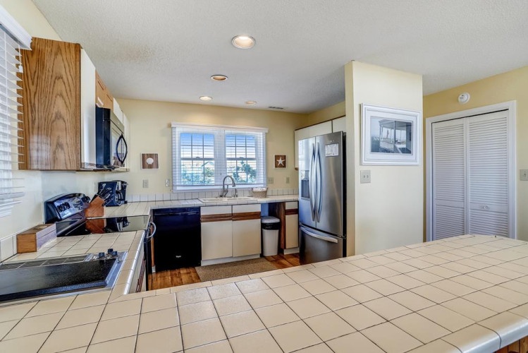 Your fully-equipped kitchen awaits with stainless appliances, tile counters, and plenty of natural light—perfect for preparing meals together during your stay.