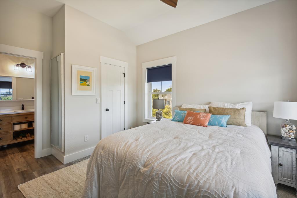 Sink into crisp linens and colorful pillows in your serene bedroom suite. Natural light fills the space, highlighting the coastal artwork and your ensuite bathroom. Wake up refreshed and ready to explore.