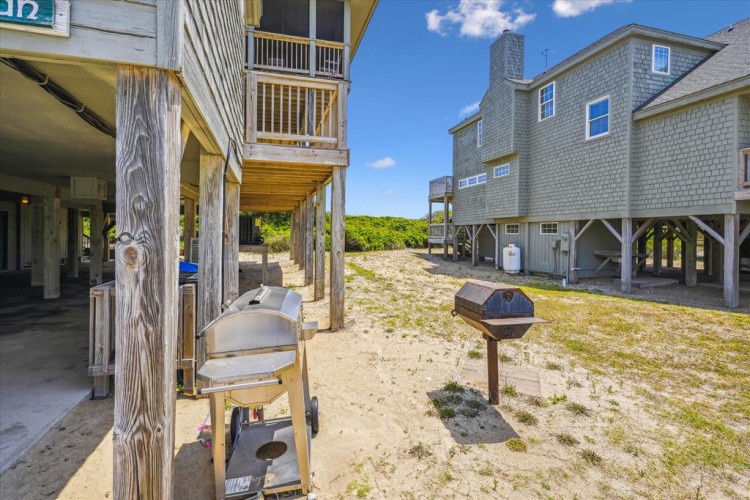 This beachside rental features elevated construction typical of coastal properties, with natural dune landscaping and access to outdoor amenities in a sandy, residential setting.
