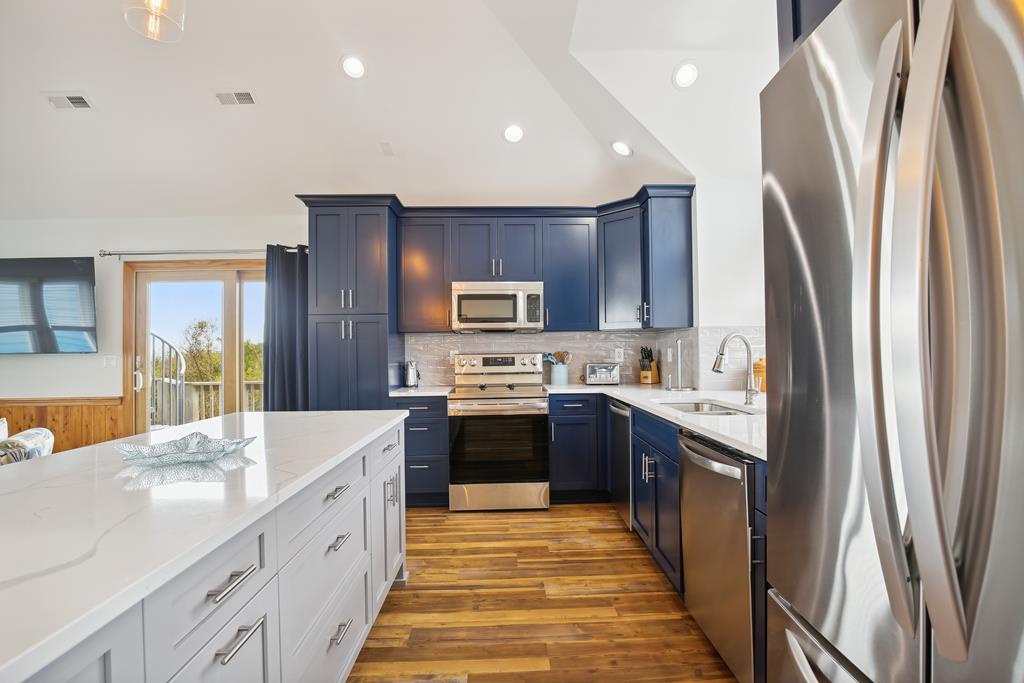 Your modern kitchen awaits with sleek navy cabinetry, stainless appliances, and a spacious island—perfect for cooking up memories in this bright, open space.