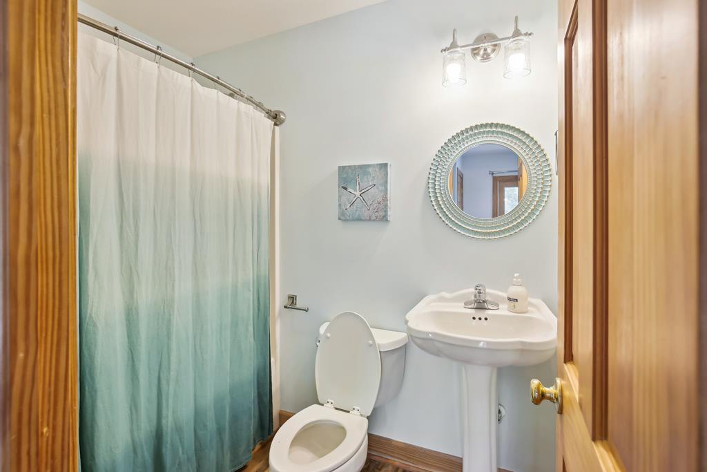 A spotless bathroom with coastal charm. Enjoy your own private space featuring a stylish round mirror, ocean-inspired shower curtain, and fresh, clean linens ready for your arrival.