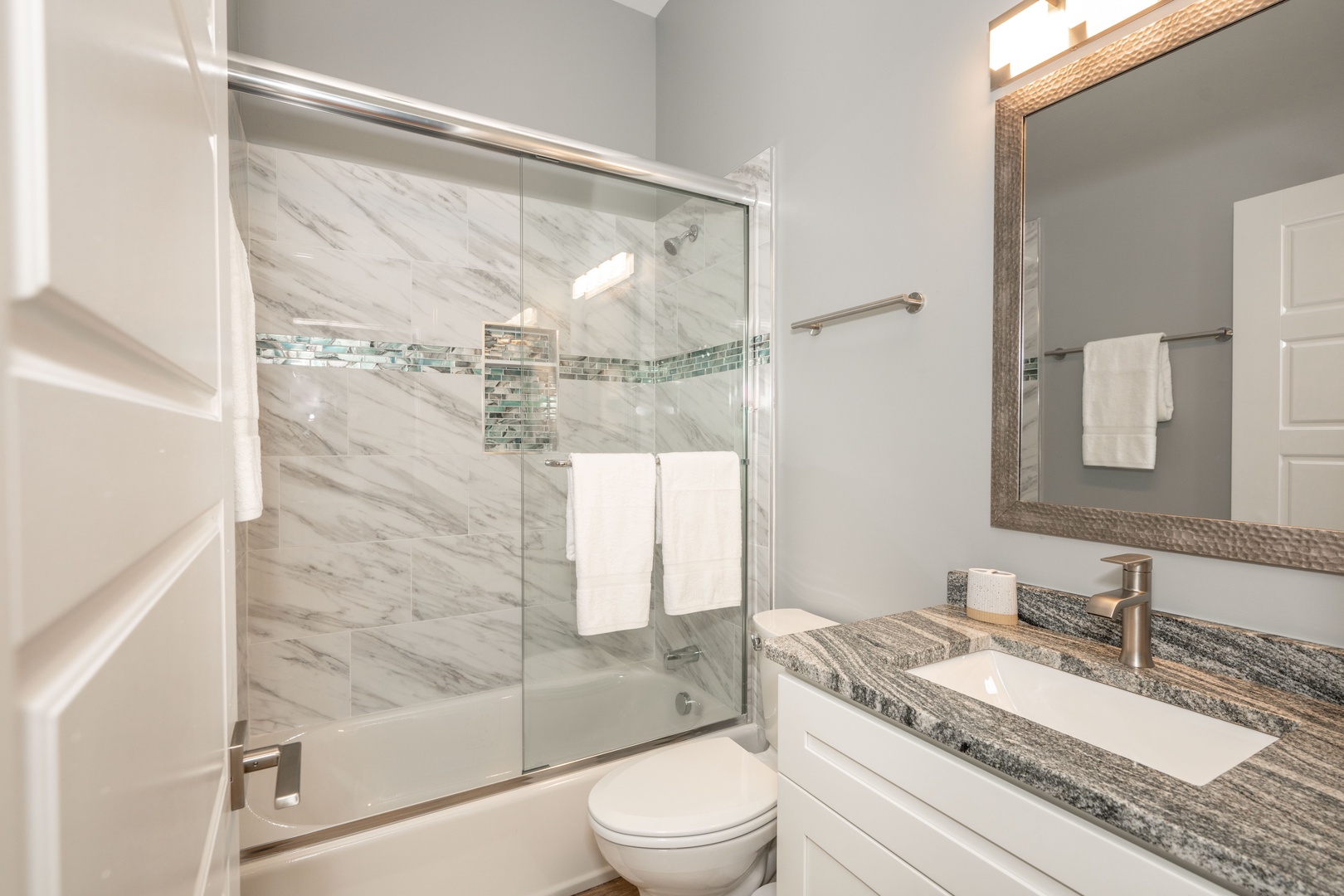 The chic full bathroom offers a single vanity & shower/tub combo