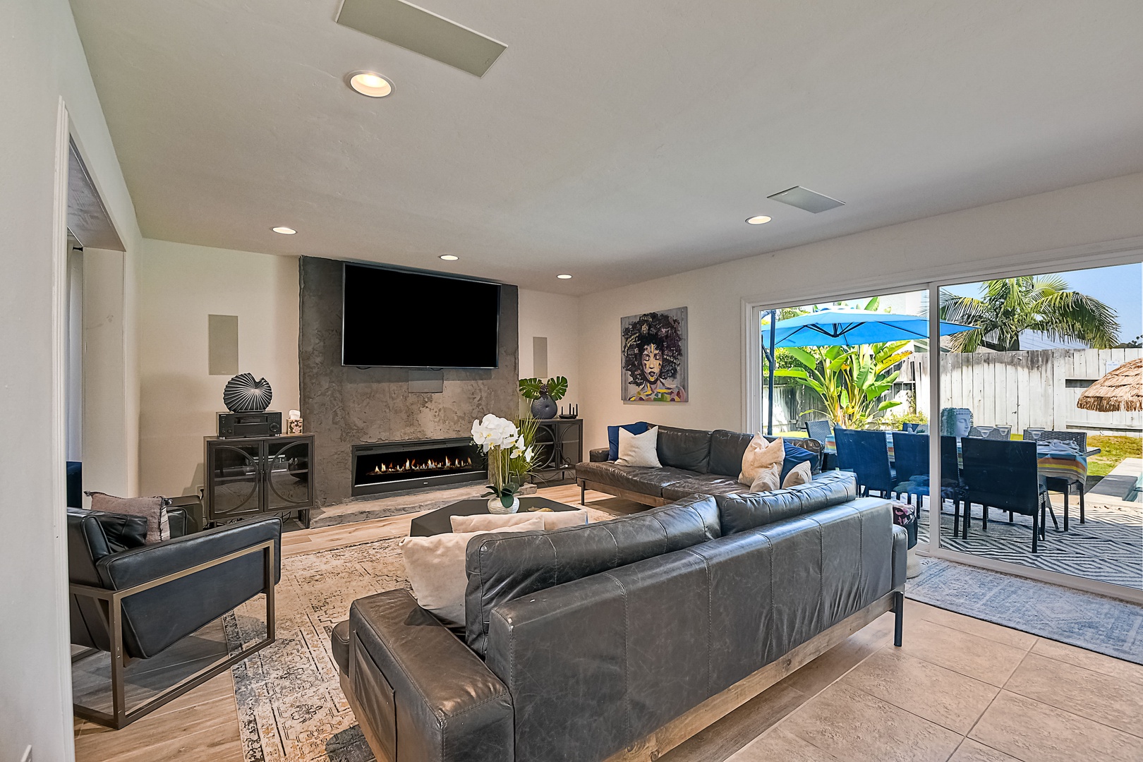 Bright living room with leather sofa, fireplace, and Smart TV