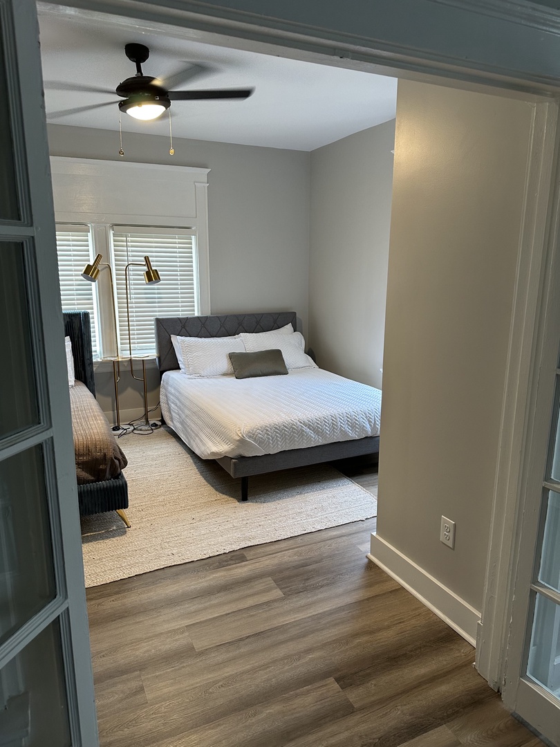 The stylish bedroom includes 2 queen beds, ceiling fan, & dresser