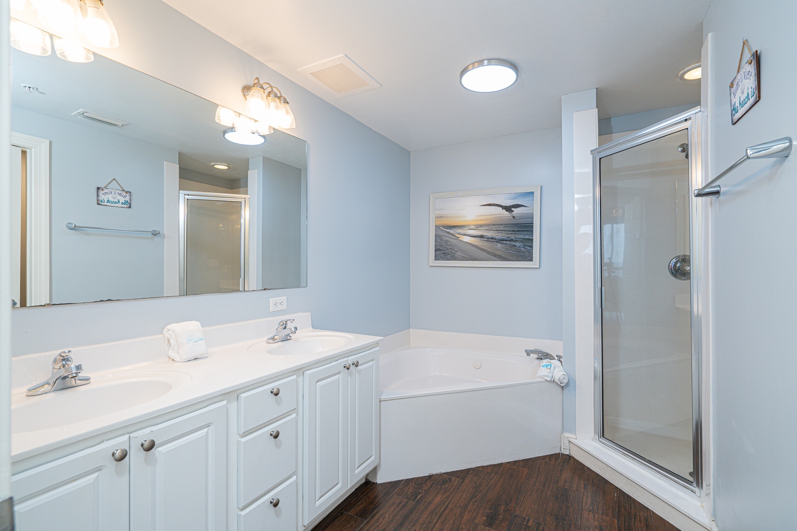 The master ensuite showcases a double vanity, soaking tub, & glass shower