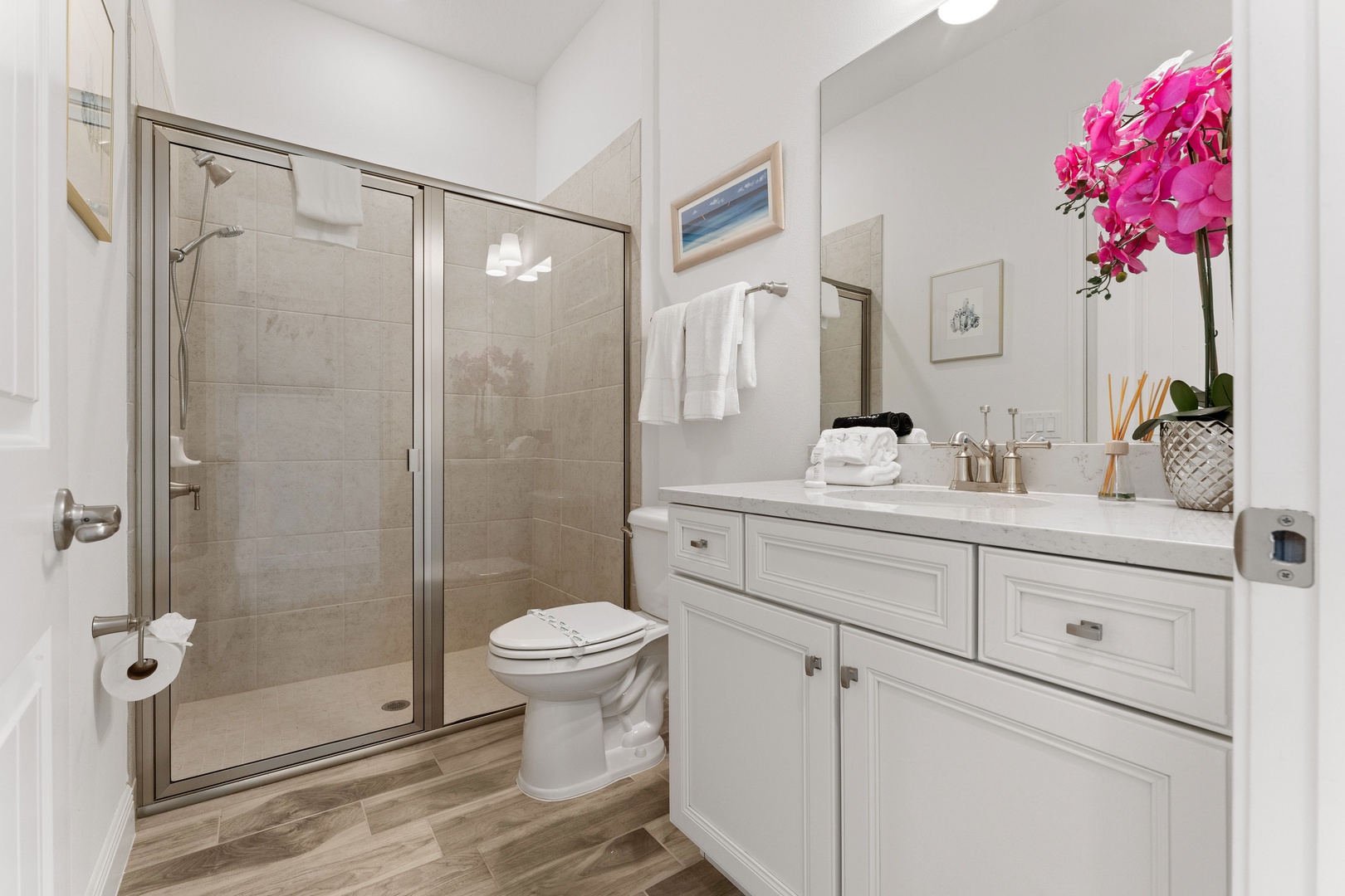 This charming ensuite bath features a single vanity & glass shower