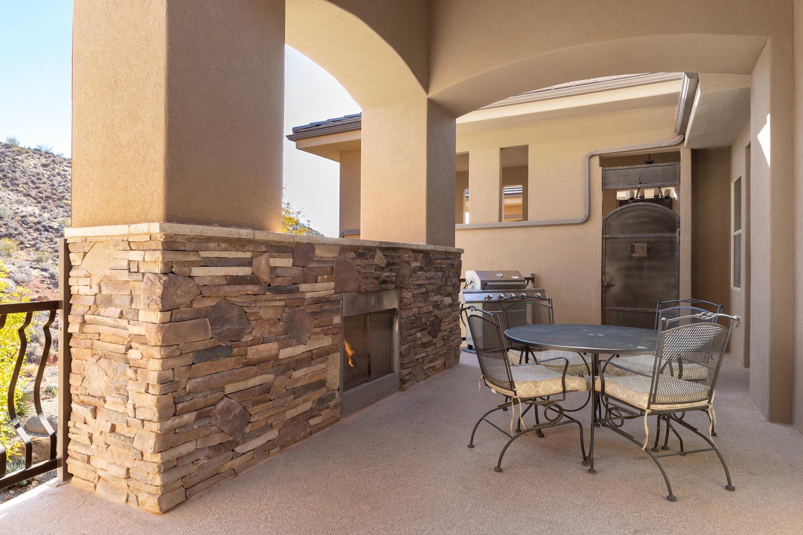 Outdoor patio with fireplace, gas grill, and dining table