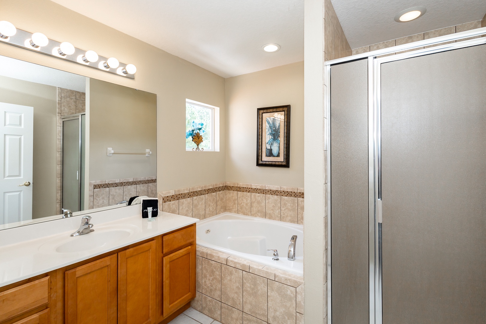 This queen en suite offers an oversized vanity, glass shower, & soaking tub