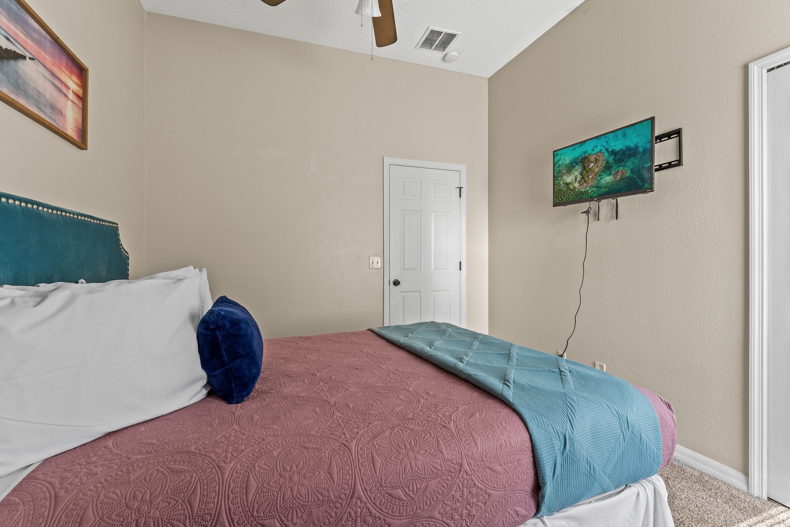 Comfortable queen bedroom featuring g a ceiling fan & smart TV