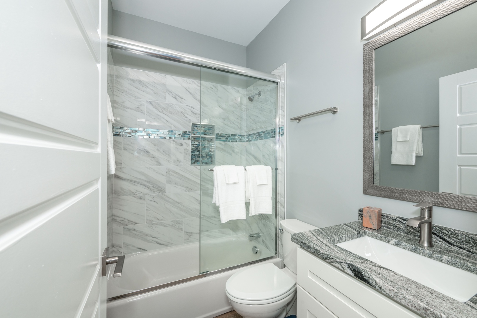 The sleek full bathroom offers a single vanity & shower/tub combo