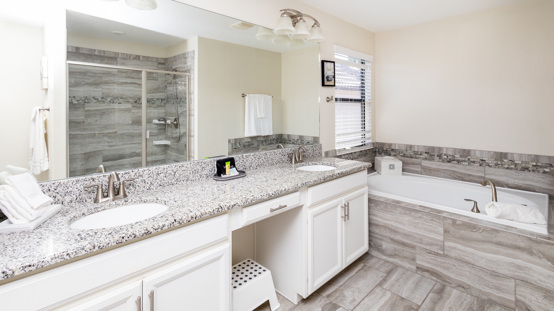 This ensuite bath features a double vanity, glass shower, and soaking tub