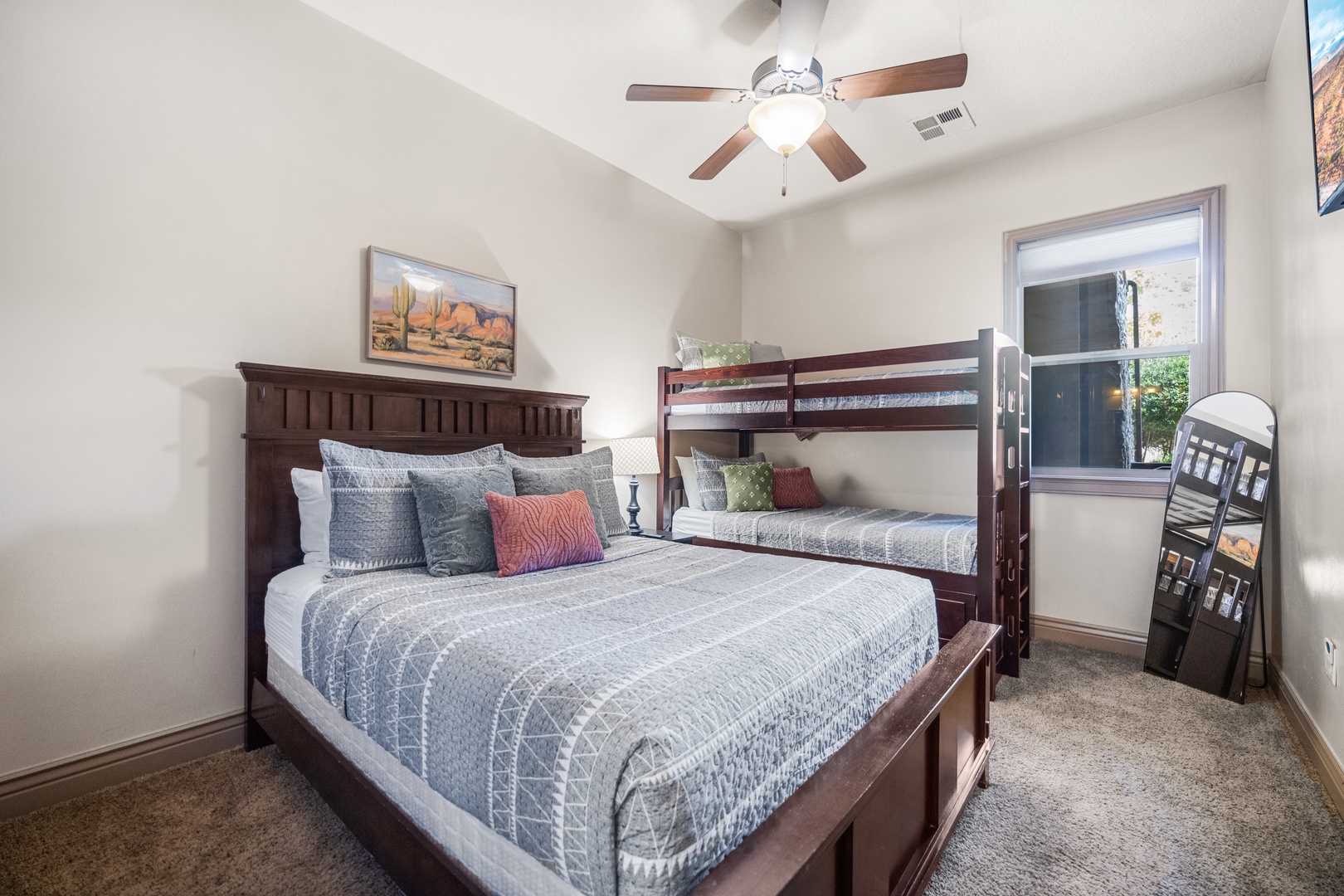 The serene second bedroom contains a queen & twin bunk bed & Smart TV