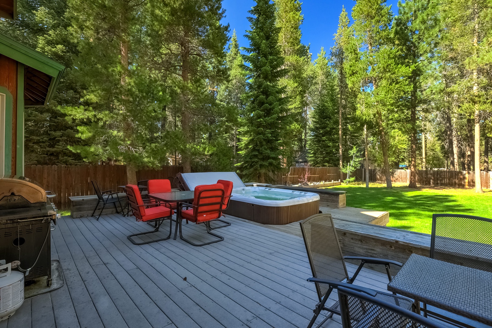 Spacious fenced in backyard with hot tub, gas BBQ, and patio seating
