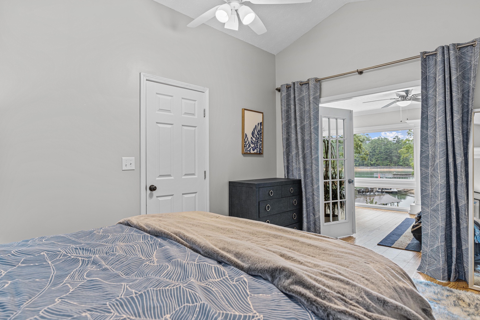 The primary bedroom offers a queen bed, ceiling fan, & sunroom access