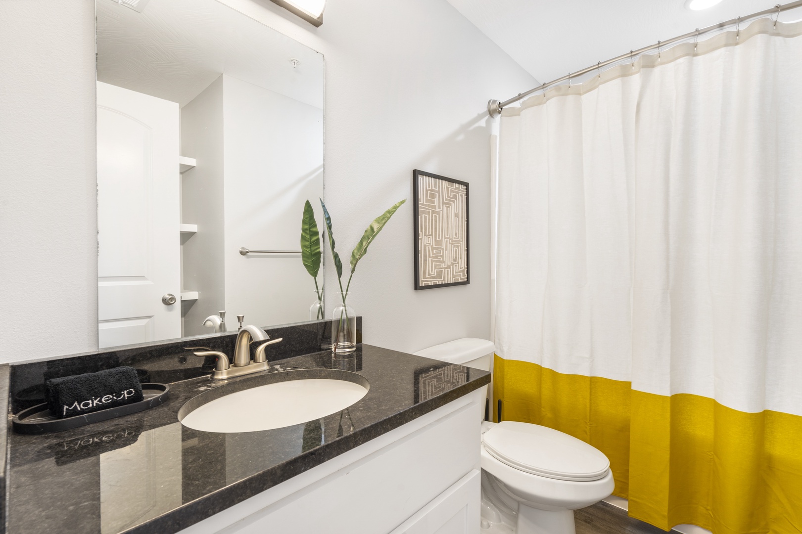 The chic bathroom contains a single vanity & shower/tub combo