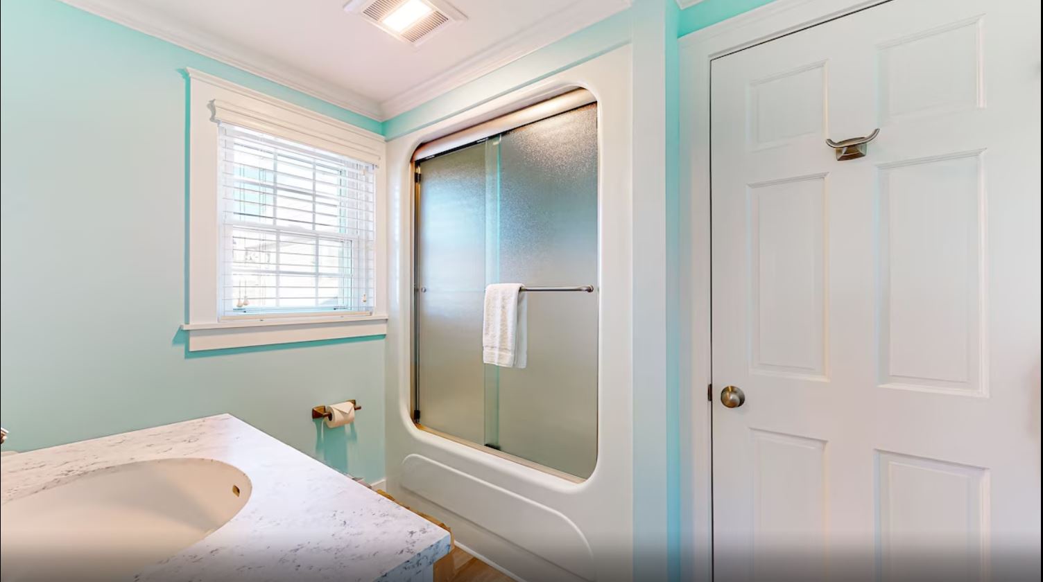 Shared bathroom with single vanity and glass-enclosed shower