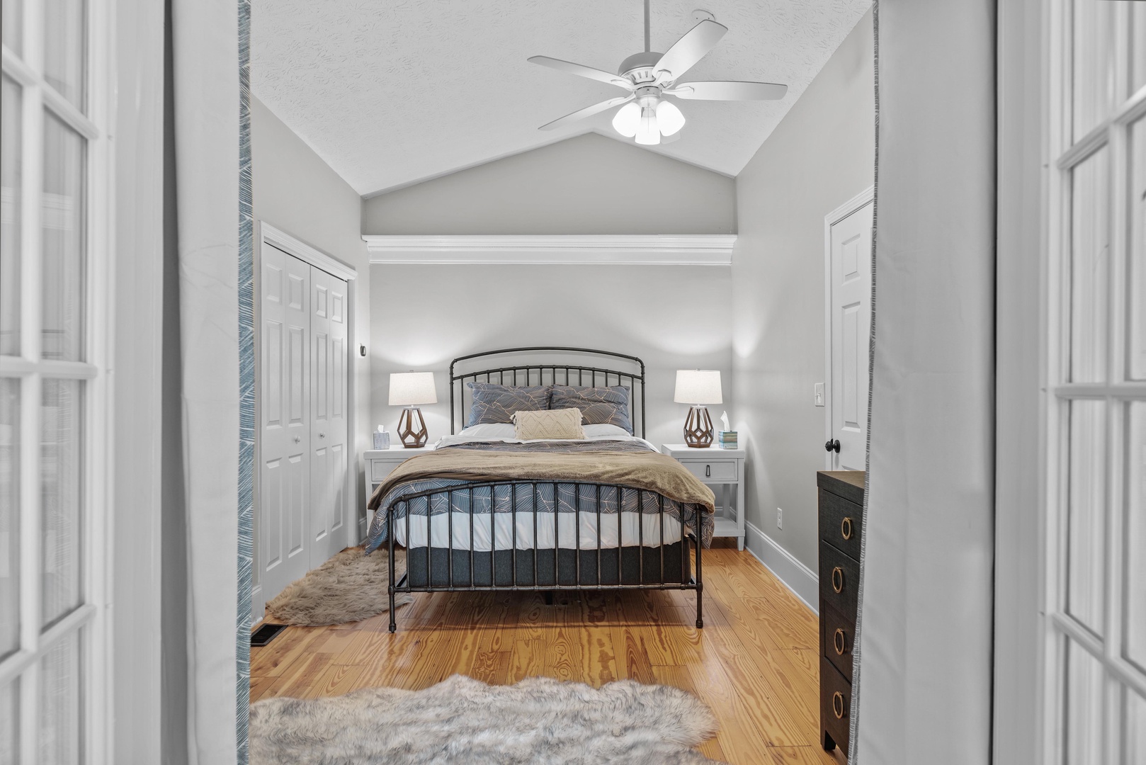The primary bedroom offers a queen bed, ceiling fan, & sunroom access