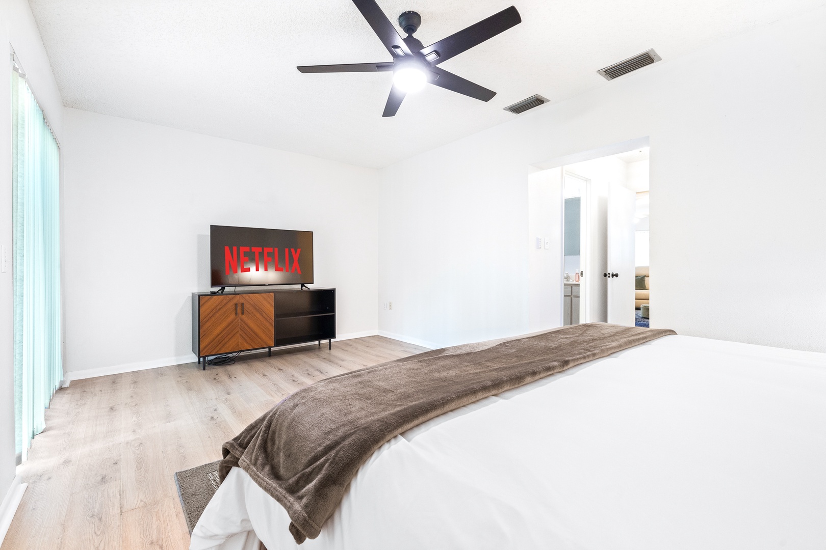 The spacious master bedroom boasts a king bed, smart TV, & patio access