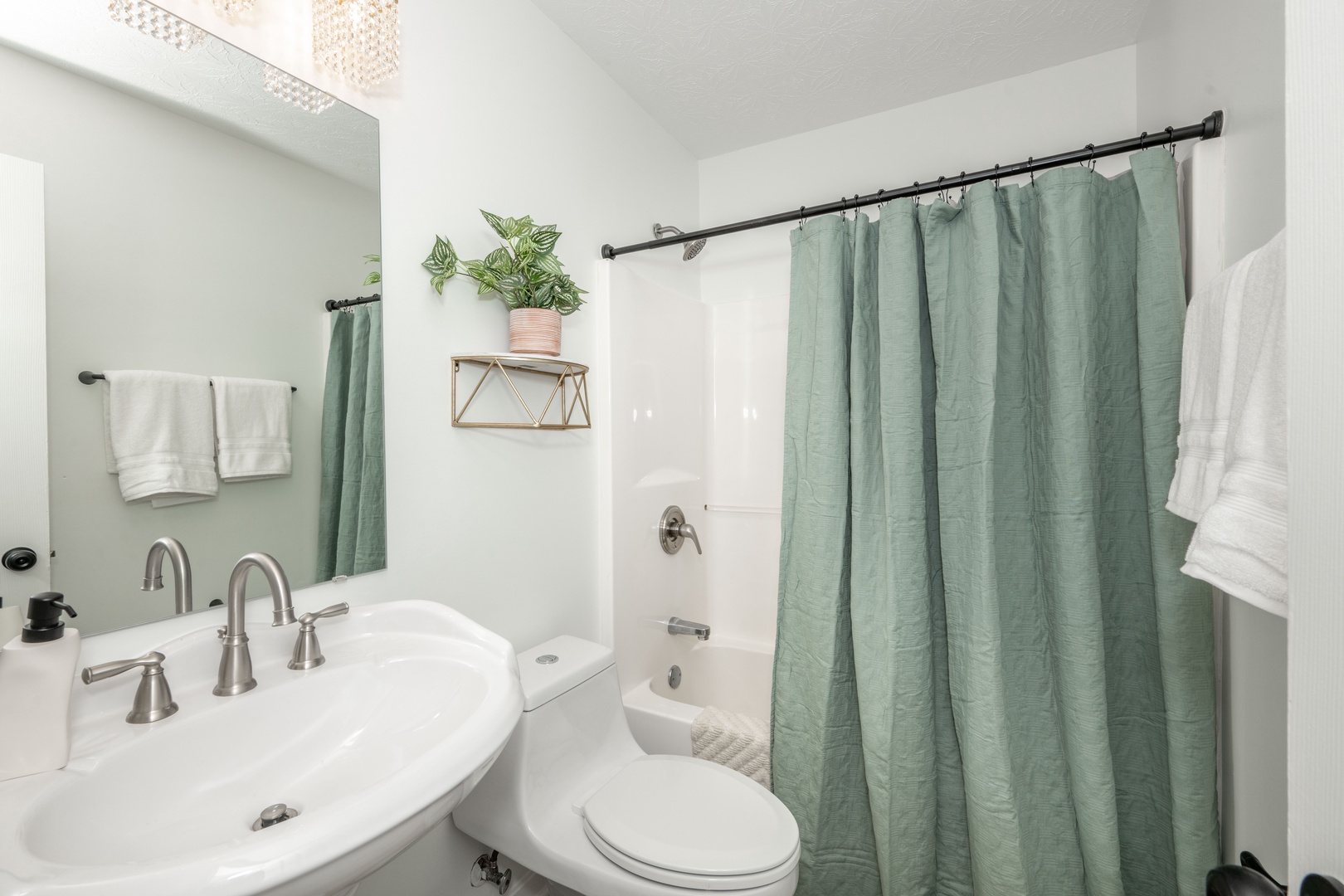 This full bathroom provides a pedestal sink & shower/tub combo